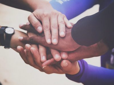 A diverse group of people joins hands